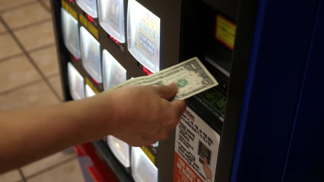 Woman inserts a dollar bill into a lottery machine