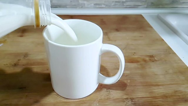 fresh white milk pouring into drinking glass on kitchen background, shooting with slow motion, diet and healthy nutrition breakfast concept
