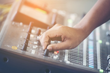 professional stage sound mixer closeup at sound engineer hand using audio mix slider working during...