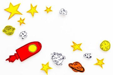 Space tourism concept. Drawn rocket or spaceship near stars, planets, asteroids on white background top view copy space