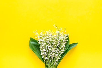 Small and fragrant spring flowers. Bouqet of lily of the valley flowers on yellow background top view copy space