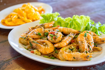 Thai food. Shrimps fried with chillies and salt served with vegetables on wood table of blurred background in the best seaside restaurants.