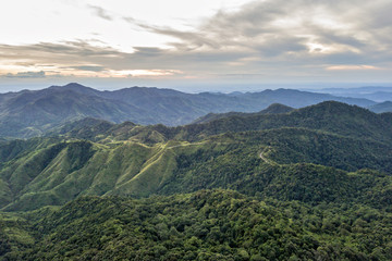 Aerial view of rainforest with mist and sunlight in the morning, view of natural high mountain with cloud and sky.