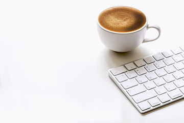 cup of coffee and white keyboard on white table