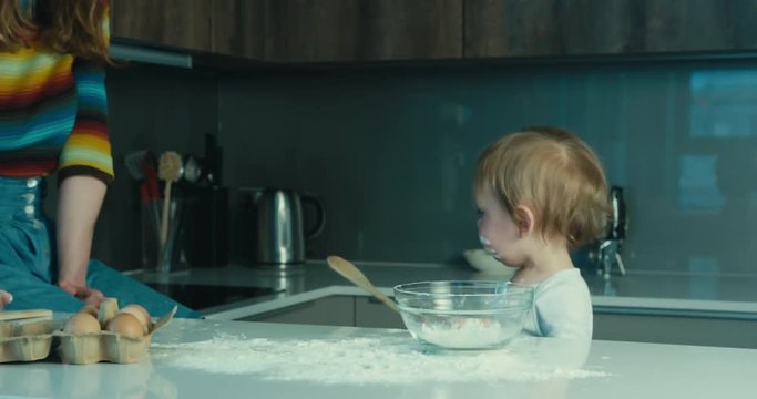 Little toddler boy stirring bowl of flour
