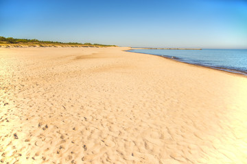 Fototapeta na wymiar lonesome beach of the Baltic Sea with blue sky and sail boat