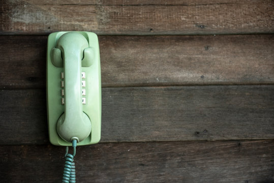 Old green telephone on wooden wall