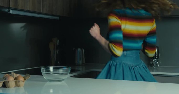 Young woman jumping and dancing in kitchen