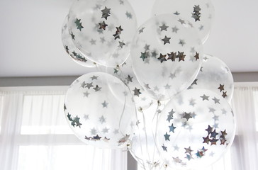 Flying white balloons with silver stars under the ceiling