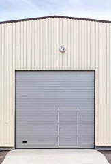 Poster de jardin Bâtiment industriel industrial warehouse exterior. closed gray metal gate with door