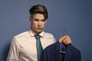 serious man in a suit. Man in white shirt, necktie hold jacket on hanger