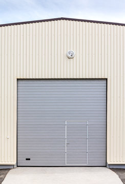 industrial warehouse exterior. closed gray metal gate with door