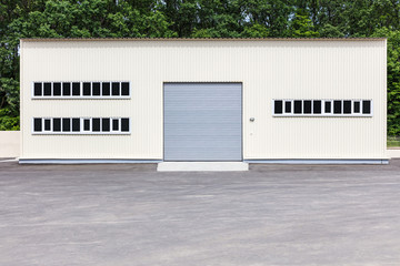 white industrial building facade with closed grey roller shutter gate