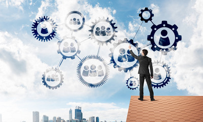 Businessman on house roof presenting teamwork and connection concept. Mixed media