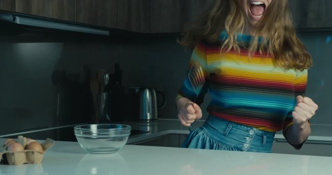Young woman dancing with spatula in kitchen
