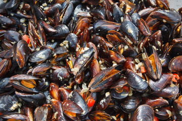 Mussels cooked in sauce with vegetables in a frying pan