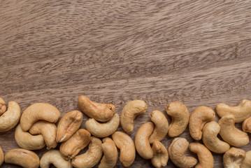 Raw cashew nuts in bowl on textured wooden background, table top view