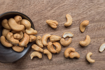 Raw cashew nuts in bowl on textured wooden background, table top view