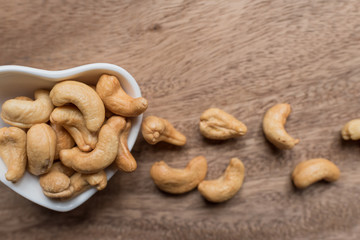 Raw cashew nuts in bowl on textured wooden background, table top view