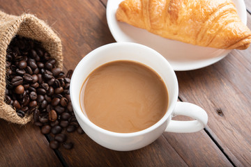 Coffee and croissant on wooden background