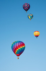 Obraz premium Four Hot Air Balloons Flying High in a Clear, Blue Sky at the Hot Air Balloon & Kite Festival in Grants Pass, Oregon