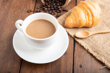 Coffee and croissant on wooden background