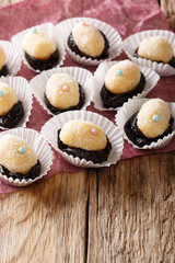 Delicious Brazilian Olho de sogra sweets from condensed milk, prunes and coconut in sugar close-up. vertical