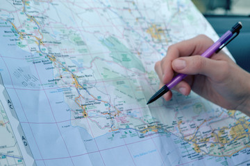 Pointing and planning a road trip on a paper travel map