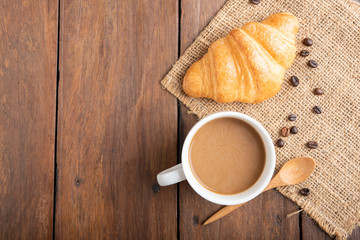 Coffee and croissant on wooden background