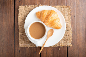 Coffee and croissant on wooden background