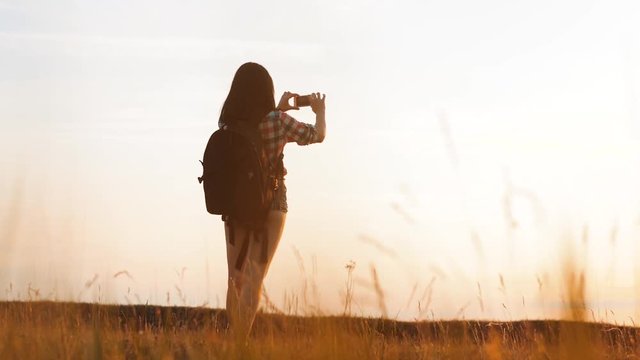 Hipster hiker silhouette girl is shooting video of beautiful nature sundown on cell telephone smartphone slow motion video. Female tourist is taking photo with mobile phone camera. female girl tourist