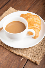 Coffee and croissant on wooden background