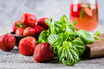 Ingredients for Summer Drink Strawberry Basil Lemonade on concrete table background. Close-up