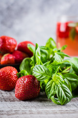 Ingredients for Summer Drink Strawberry Basil Lemonade on concrete table background. Close-up