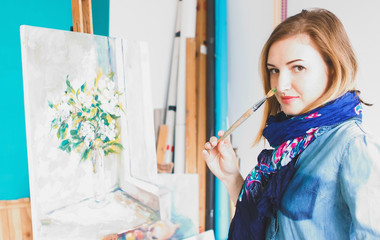 portrait of a girl painter with a palette of colorful paintings in an art studio. Thoughtful artist,