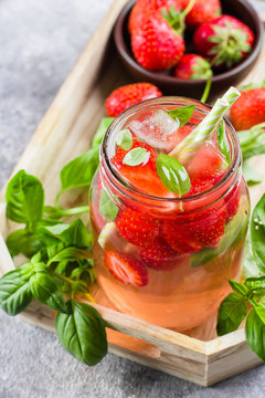 Summer Food and Drink. Strawberry lemonade with basil in mason jar on wooden tray on concrete table. Top view, copy space