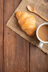 Coffee and croissant on wooden background