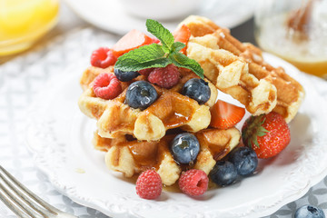 Fresh homemade waffles with raspberries, strawberries, blueberries and honey. Delicious Breakfast with berries