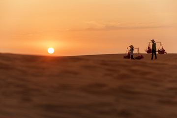 Woman carrying flower basket at sunset in Mui Ne sand dune, Vietnam