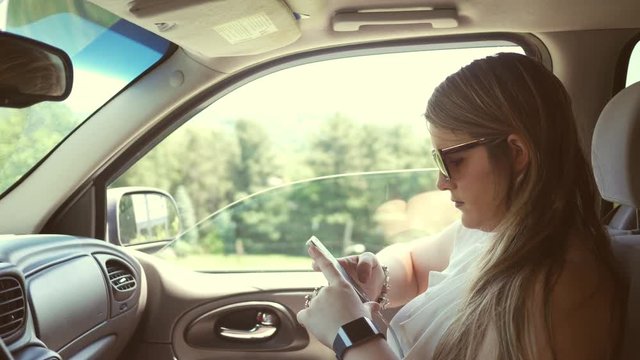 Woman reads her smart phone messages in passenger seat of parked SUV
