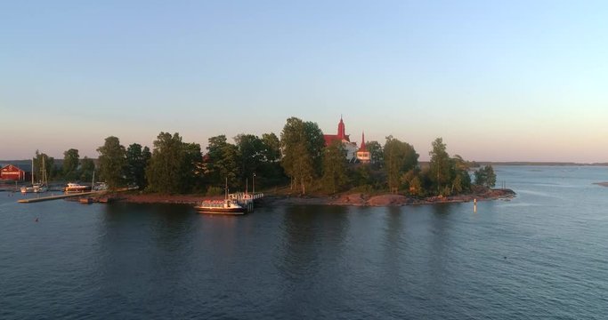 House on a island, C4K aerial rising tilt view of a restaurant at a isle, at the south harbor of Helsinki, on a sunny summer evening dusk, in Helsingfors, Finland