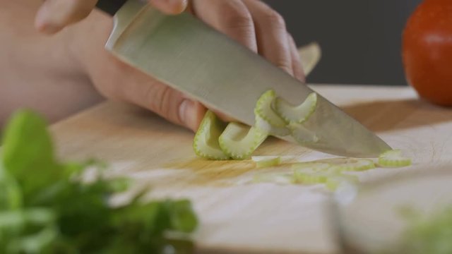 hand of an expert chef cuts celery