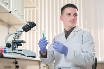 A young man scientist or doctor working with test tubes in lab