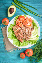 Grilled chicken breast with buckwheat porridge, tomatoes and avocado on blue wooden background. Diet nutrition, healthy food for lunch.