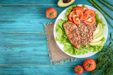 Grilled chicken breast with buckwheat porridge, tomatoes and avocado on blue wooden background. Diet nutrition, healthy food for lunch.
