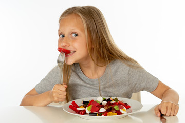 happy young girl holding a plate full of candy lollies on white background