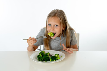 happy healthy yong girl eating her broccoli vegetables in healthy eating concept