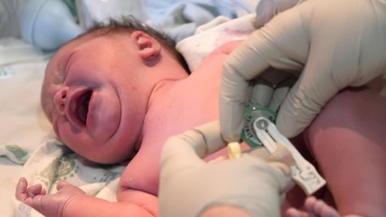 A cute newborn baby girl right after birth getting checked up