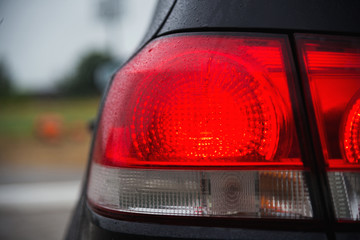Black sports hatchback car rear light after the rain coseup