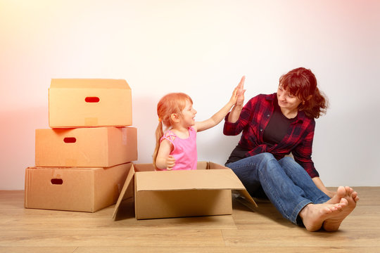 Mom And Daughter Put Things Out Of The Boxes After Moving To A New House. The Joy Of Buying New Homes